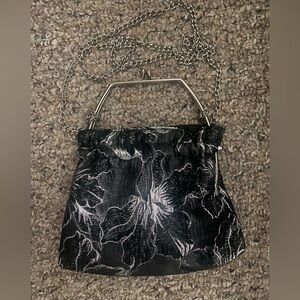 Black and silver purse with handle and silver cross body chain.